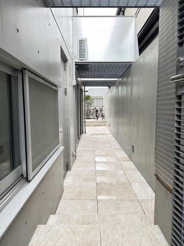 賃貸併用住宅の共用部側アプローチです。コンクリートの質感高く、隅々まで手入れの行き届いた綺麗な状態をご覧いただけます。2024年に大規模修繕を施しており、購入後の維持管理面でも安心のクオリティです。
